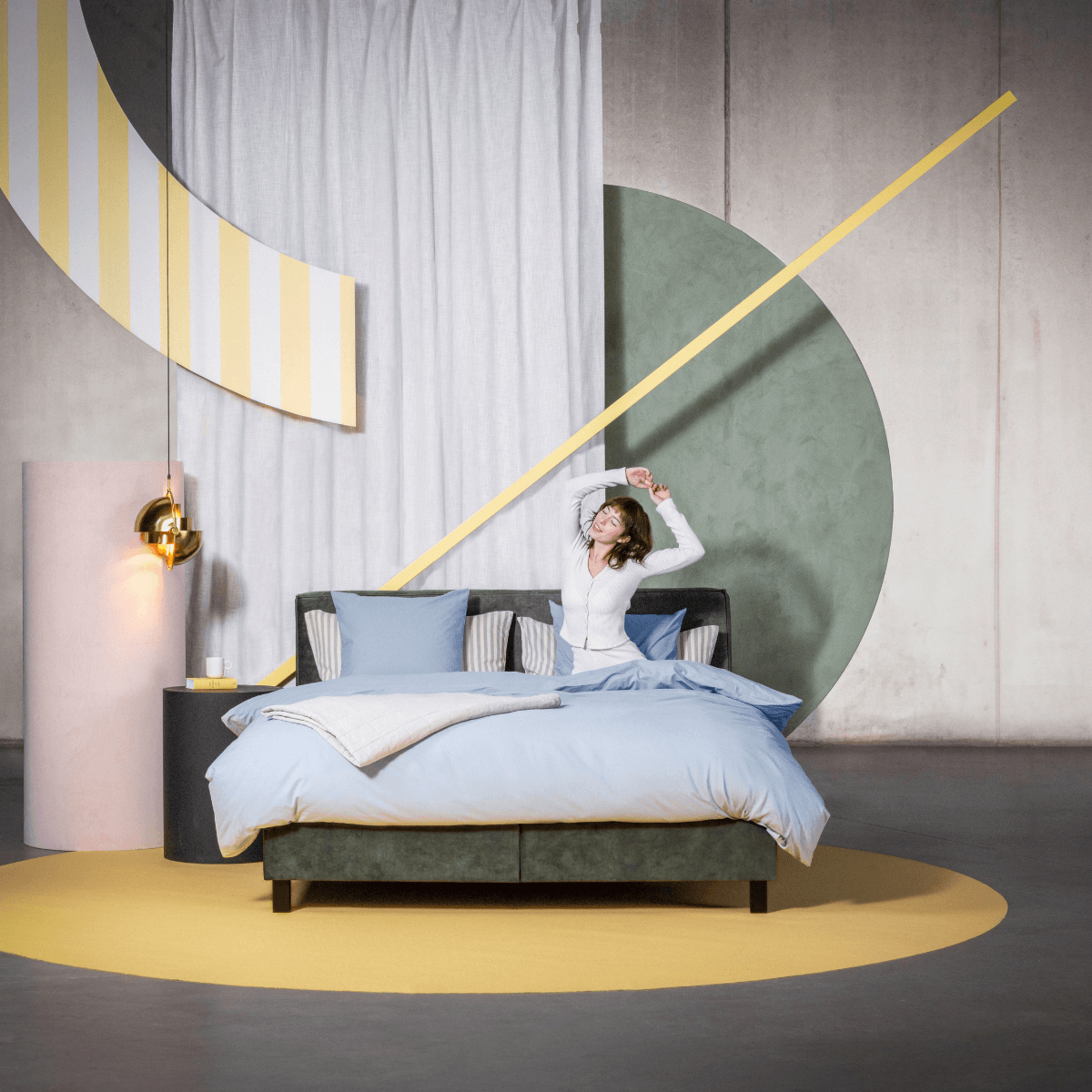 Woman relaxing on a custom bed with blue bedding, surrounded by colorful geometric decor.