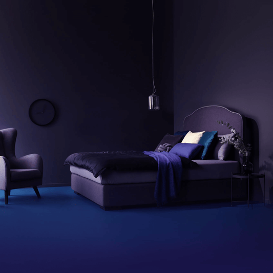 Stylish custom bed with purple fabric and cozy throw in a modern bedroom setting with matching armchair.